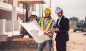 drainage design - Two engineers reviewing a drainage plan at a construction site, discussing layout and water flow management strategies