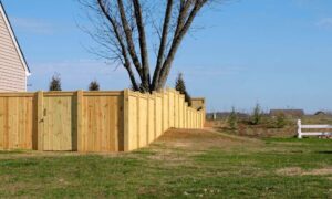 A wooden backyard fence positioned near a property line survey marker, suggesting a boundary concern