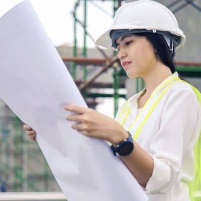 Female engineer reviewing construction plans on site, illustrating the technical planning and updates involved in modern roadway design work