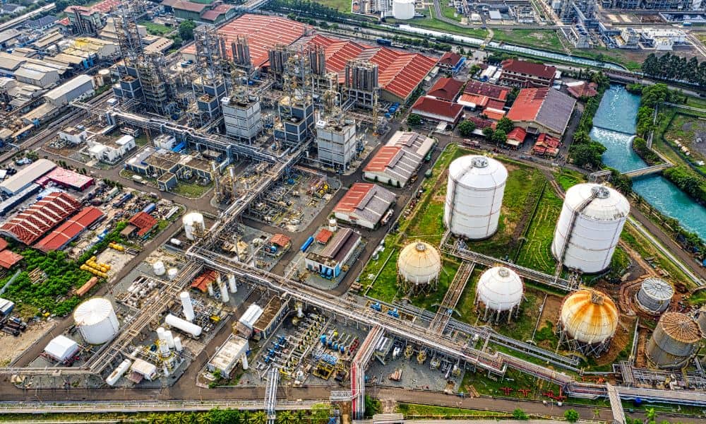 A wide aerial view taken during drone surveying, showing tanks, pipelines, and complex structures across a large industrial site