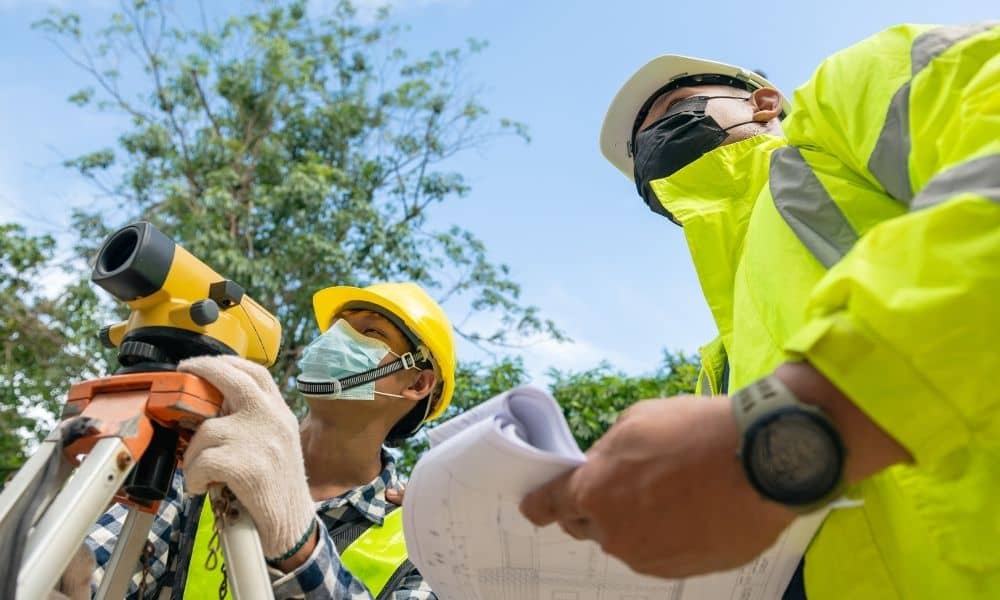 Licensed land surveyors reviewing site plans and performing field measurements on a job site