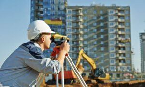 Land surveyor using a theodolite at a commercial property construction site during an ALTA survey