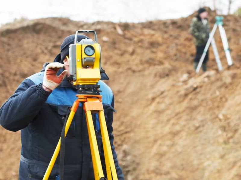 Surveyor using total station to verify property boundaries for legal compliance