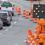 Traffic control signs and lane closure indicators with cars on a busy road in Arlington showing technology used to improve safety

