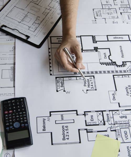 Engineer reviewing site blueprint - ALTA SURVEY Texas Engineer reviewing subdivision engineering plans and drainage layouts on blueprints with calculator and measuring tools