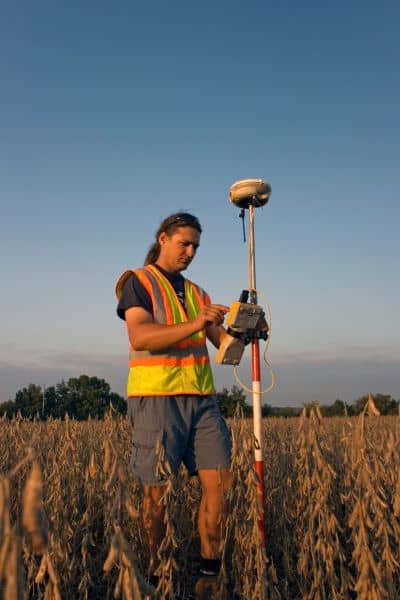 A land surveyor using GPS equipment to map a corner point during a boundary line survey
