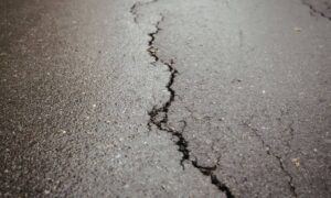 Cracked asphalt pavement highlighting how geotechnical engineering affects soil stability beneath road surfaces