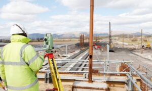 Commercial site layout measurement - ALTA SURVEY Texas Surveyor using a total station during a construction survey on a large commercial development site