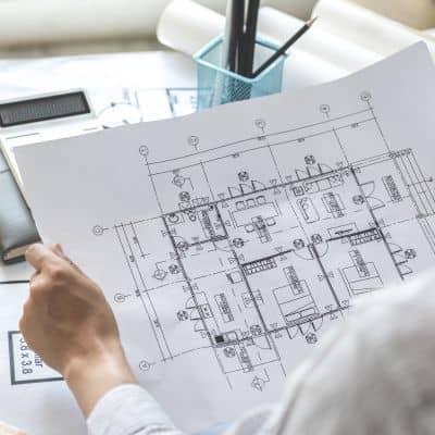 Reviewing detailed construction plans - ALTA SURVEY Texas An engineer reviewing detailed construction plans to coordinate site work
