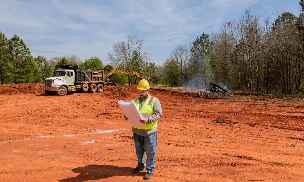Reviewing site plans at active project site - ALTA SURVEY Texas A construction engineer reviewing plans on an active project site during early site work