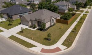 Drone view of a residential corner lot in Texas showing two street frontages and the surrounding subdivision
